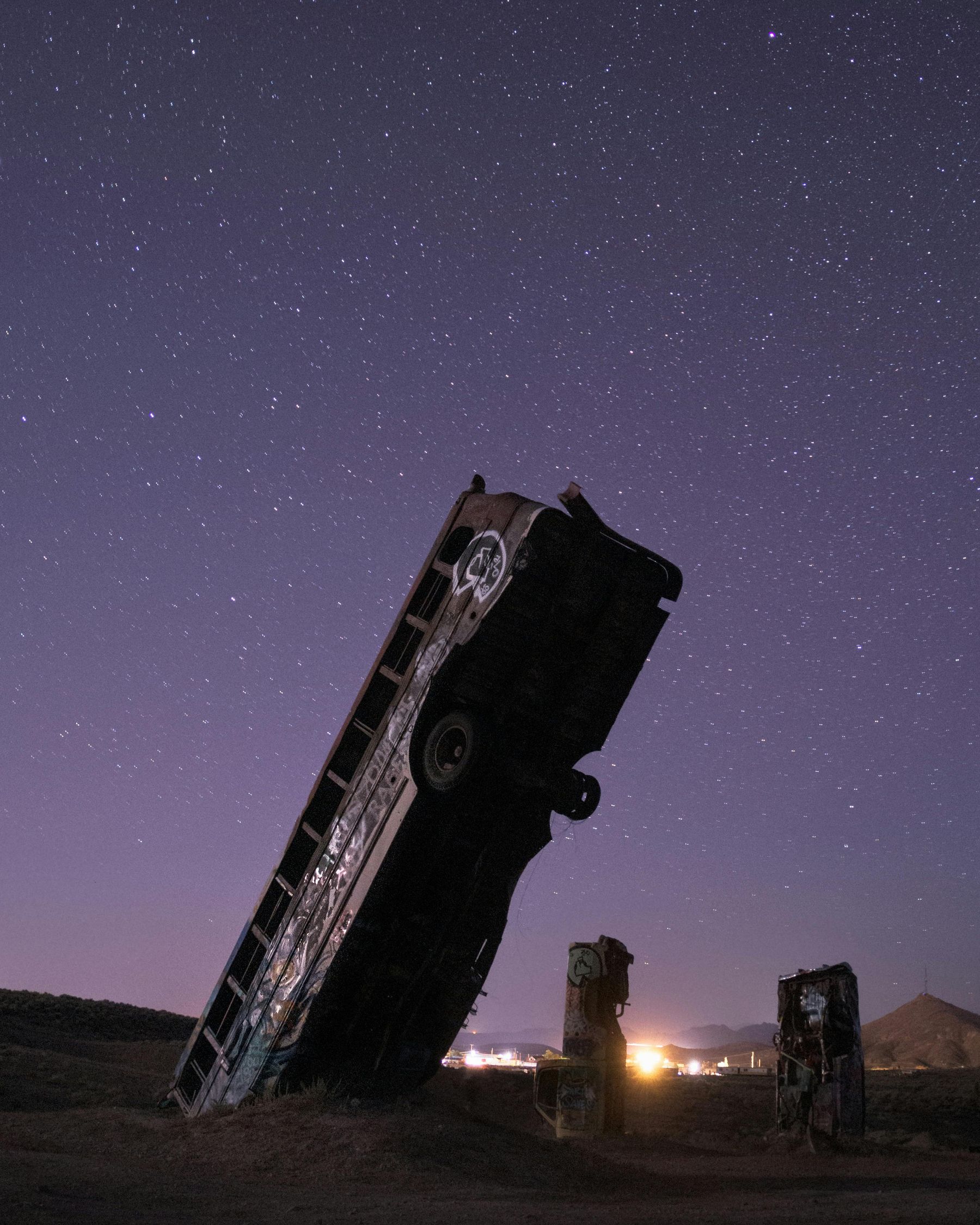 Tour bus planted in the desert under a starry night sky