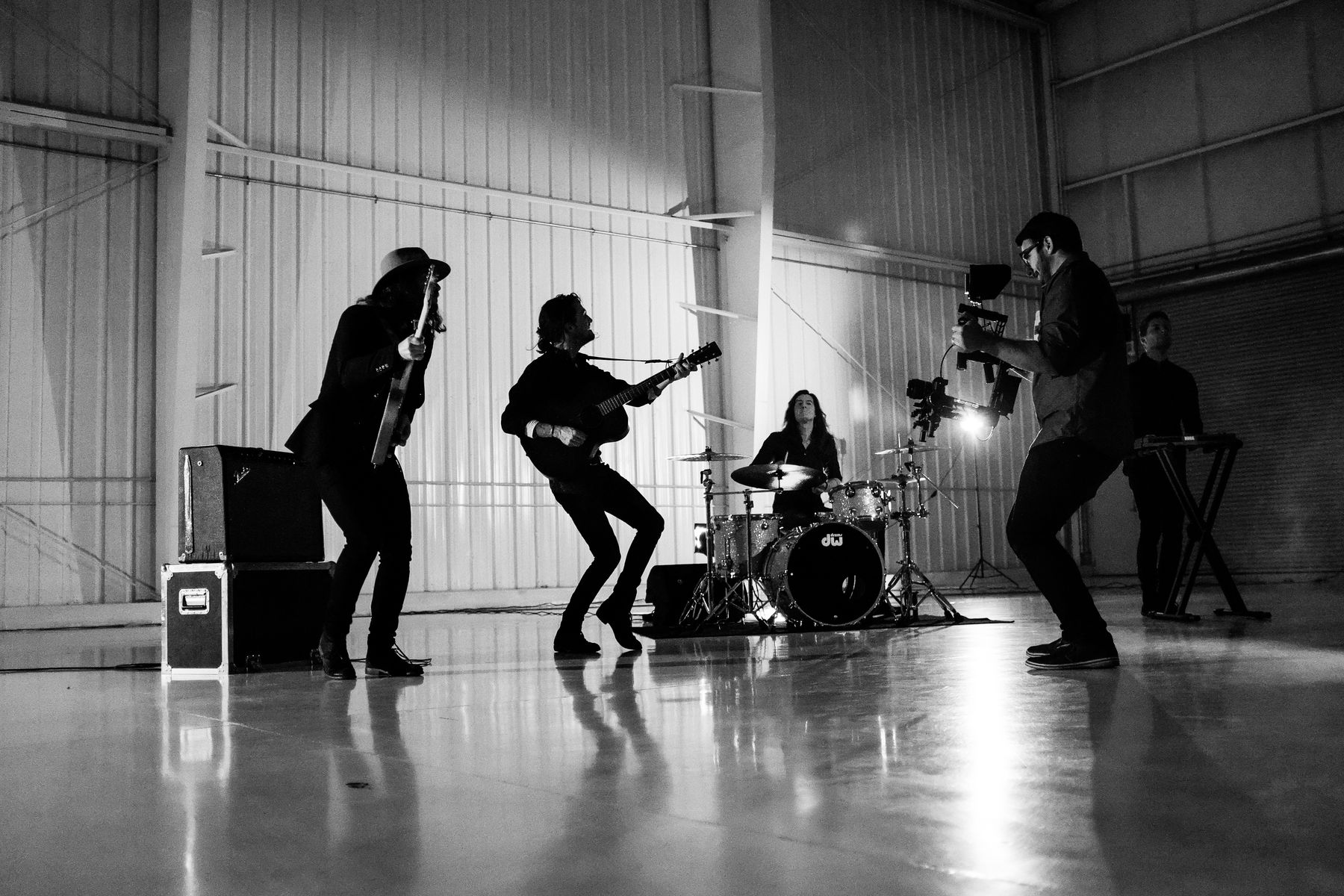 Band performing in a warehouse studio while being filmed